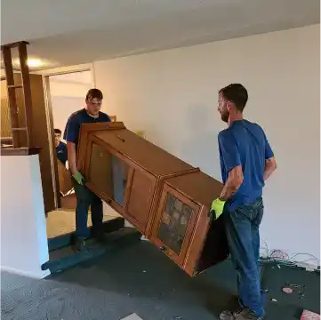 Two employees of Junk Amigos Charlotte carrying a sofa during a furniture junk removal service.