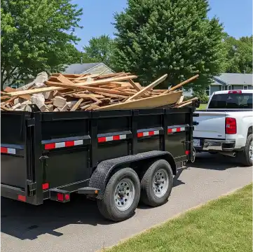 Junk removal truck loaded with items next to a driveway.