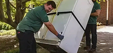 Two employees of Better Call Jon Junk Removal  in The Santa Clarita Valley Area, loading an appliance during a junk removal service.