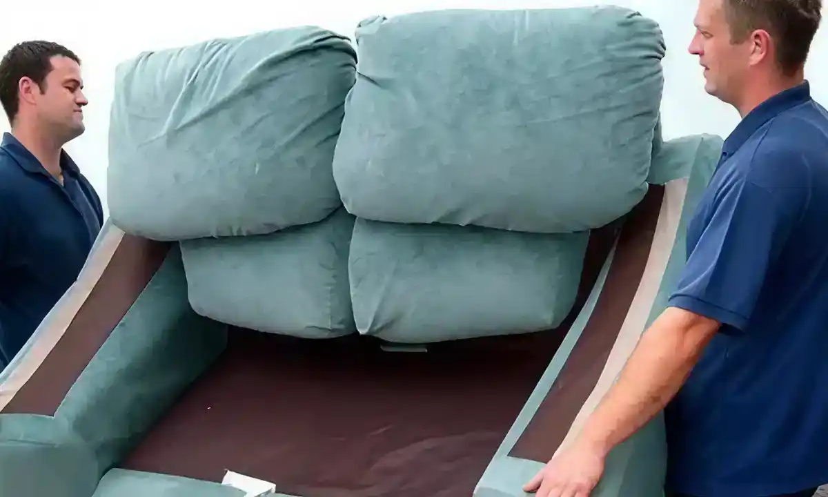 Two employees of JunkDunk carrying furniture during a junk removal service.